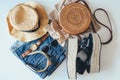 Women`s summer clothes collage on white, flat lay. Woven sandals, rattan bag, hat, watch, shorts, sunglasses top view Royalty Free Stock Photo