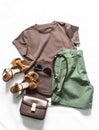 Women`s summer clothing walking set - brown t-shirt, cotton green shorts, suede sandals, leather cross body bag on a light Royalty Free Stock Photo