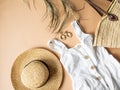 Women`s summer straw hat, wicker bag, white sundress, sunglasses and jewelry on a beige background. Copy space. Top view