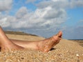 Women`s tanned legs on the sea sand Royalty Free Stock Photo