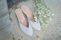 Women's wedding shoes patterned and white next to flowers