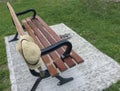 Women`s straw hat hanging on wooden park bench and shoes beside it