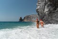 Women in Santa Claus hats run into the sea dressed in red swimsuits. Celebrating the New Year in a hot country Royalty Free Stock Photo