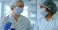 Women scientists in lab coats analyzing beaker with blue solution lab bench, digital data overlays Royalty Free Stock Photo