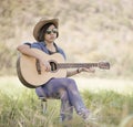 Women short hair wear hat and sunglasses sit playing guitar in g Royalty Free Stock Photo