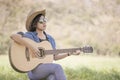 Women short hair wear hat and sunglasses sit playing guitar in g Royalty Free Stock Photo