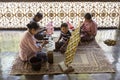 Women sitting on carpets in temple making intricate flower offerings for worshipers