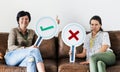 Women sitting on couch holding tick and cross icons