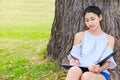 Women sitting near big tree and drawing in the park. Royalty Free Stock Photo