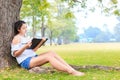 Women sitting near big tree and drawing in the park. Royalty Free Stock Photo