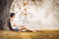 A Women sitting near big tree and writing paper in the park. Royalty Free Stock Photo