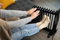 Women sitting and warming hands over and electric heater. High energy prices and cold home