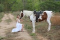 Women on white dress standing by Horse On field Against mountain. Royalty Free Stock Photo