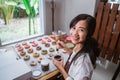 Women smile while decorating donuts with chocolate frosted, pink glazed and donut sprinkles