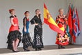 Women in flamenco dresses flying the Spanish flag