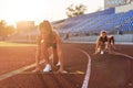 Women sprinters at starting position ready for race on racetrack.