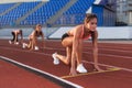 Women sprinters at starting position ready for race on racetrack.