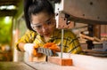 Women standing is craft working cut wood at a work bench with band saws power tools at carpenter machine in the workshop Royalty Free Stock Photo