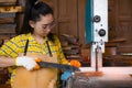 Women standing is craft working cut wood at a work bench with band saws power tools at carpenter machine in the workshop Royalty Free Stock Photo