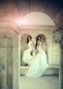 Women at stone ancient arch in summer. girls in white dress with stylish hair. Fashion model or princess in dress