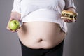 Women suffer from obesity with big hamburger and apple in hands. Junk food concept Royalty Free Stock Photo