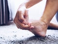 Women suffering from acute foot pain and use hands to massage on feet.