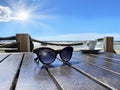 Women sunglasses and cup of coffee on wooden table top at beach on horizon blue sky and sea blue marine summer holiday background