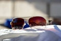 Women sunglasses lie on a beach towel.