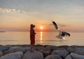 Women and sunset  in red dress and summer hat seagull fly enjoy pink summer sunset at sea nature seascape  landscape Royalty Free Stock Photo