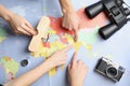 Women with tourist items planning vacation on world map, top view