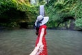 Women tourists holding man`s hand and leading him to Tibumana waterfall in Bali, Indonesia.