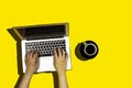 Women typing on keyboard of modern laptop and drinking a coffee isolated on yellow background Royalty Free Stock Photo