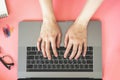 Women typing on laptop in pink pastel colourful office with accessories Royalty Free Stock Photo