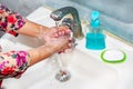 Women use liquid soap for rubbing and washing her hands under the water tap. Royalty Free Stock Photo