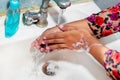 Women use liquid soap for rubbing and washing her hands under the water tap. Hygiene concept. Royalty Free Stock Photo