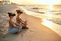 Women use VR glasses for deeper immersion. Two females doing group yoga meditation on the beach in virtual reality Royalty Free Stock Photo