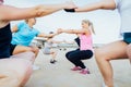 Women of various ages doing fitness workouts in class exercise with coach on beach. Ladies doing paired squat exercises