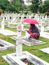 A Women Visiting Indonesian Heroes Cemetery Using a Red Umbrella