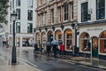 Women walk past Harvie And Hudson shop on London, UK, on a rainy day