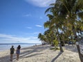 2 women walk by rows of tall coconut palm trees at Bohol Beach Club in Dumaluan Beach, Panglao Island, Bohol, Philippines Royalty Free Stock Photo