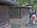 Women wear Kimono walking beside vintage wooden Japanese fence.