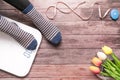 Women wear strip sock sitting with white digital scale and measuring tape on the wooden background composition health and fitness