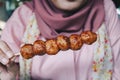 Women wearing pink veils eat Barbecue Meatballs Satay.