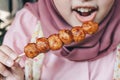 Women wearing pink veils eat Barbecue Meatballs Satay.