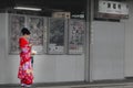 Women wearing red kimono patterned flowers stand hold smart phone under fluorescent light when it rains during journey Tofukuji