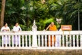 women in white clothes and orange dressed monk throw blossons into the river to honor the godness