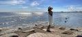 Women in white dress hat on  beach  summer sunset  sky seagull and flowers with beach plant stay on rock stone at pier   landscape Royalty Free Stock Photo