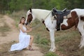 Women on white dress standing by Horses On field Against mountain. Royalty Free Stock Photo