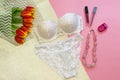 Women white lace lingerieas a gift from lover. Beautiful bouquet of red tulips, natural necklace and cosmetic tools on pink andd Royalty Free Stock Photo