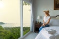 Women in white shirts, pants, weave hats Sitting and looking at the beautiful sea view from the window in the room Royalty Free Stock Photo